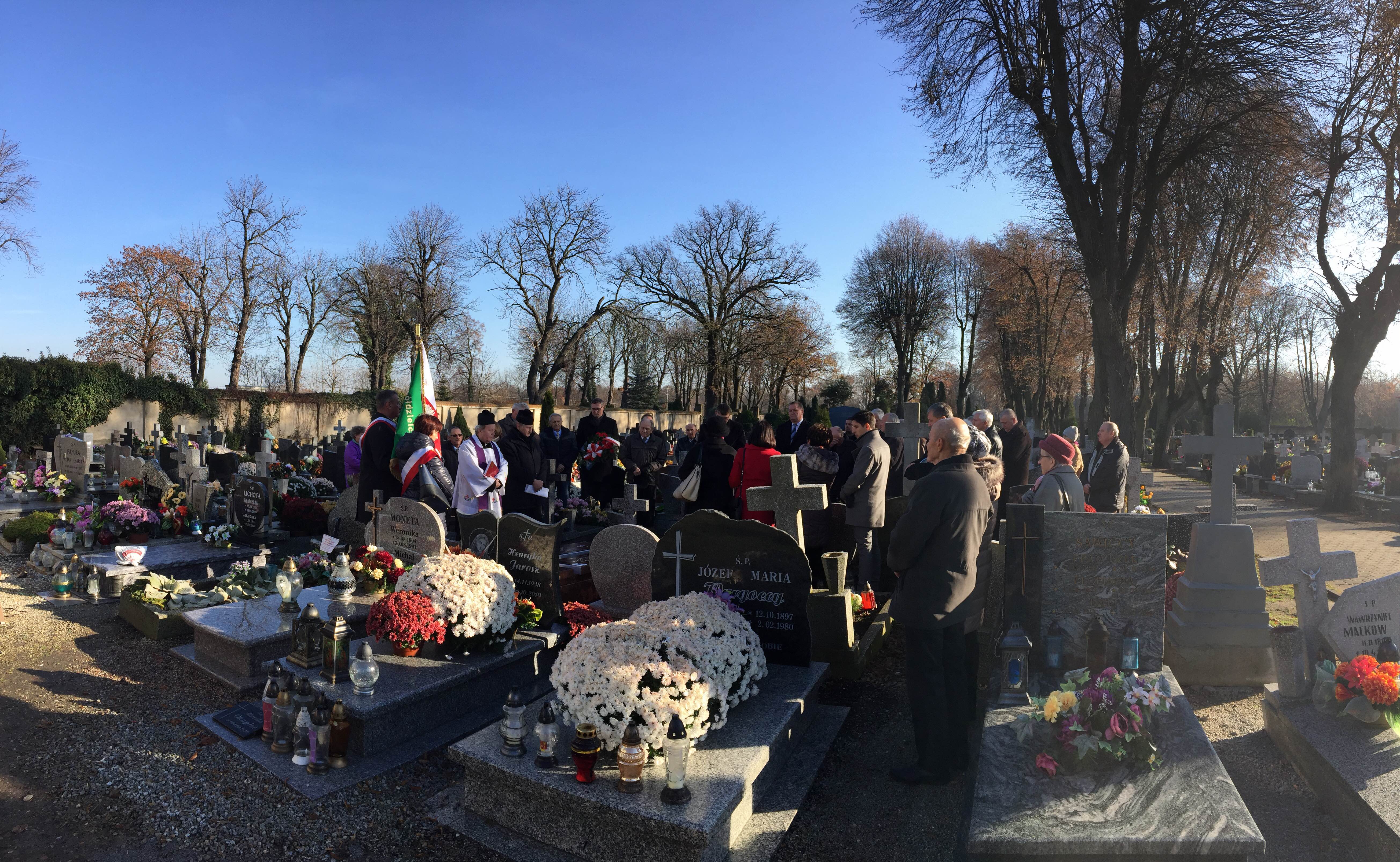 zdjęcie przedstawia grupę ludzi na cmentarzu stojących wśród pomników