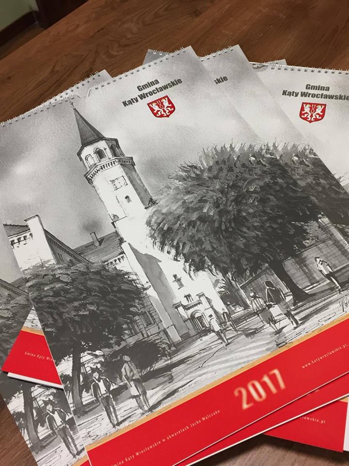 zdjęcie przedstawia ułożone na biurku kalendarze gminne na 2017 rok