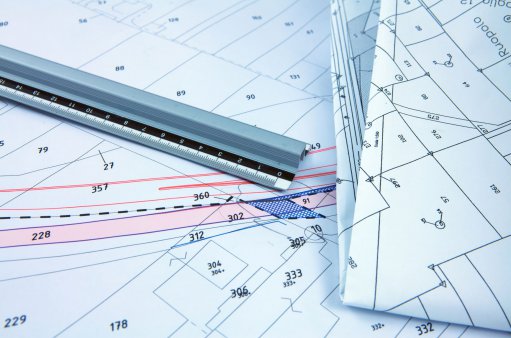 zdjęcie przedstawia mapy geodezyjne na których leży linijka
